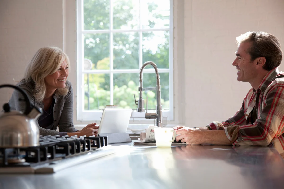 Couple souriant discutant dans une cuisine lumineuse