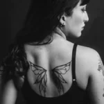 Dos tatoué d'une femme en noir et blanc, motif d'ailes
