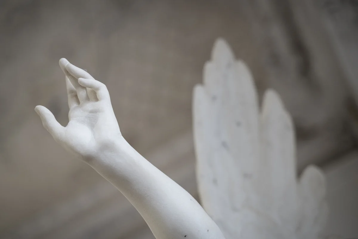 Main et aile d'une statue d'ange en marbre blanc