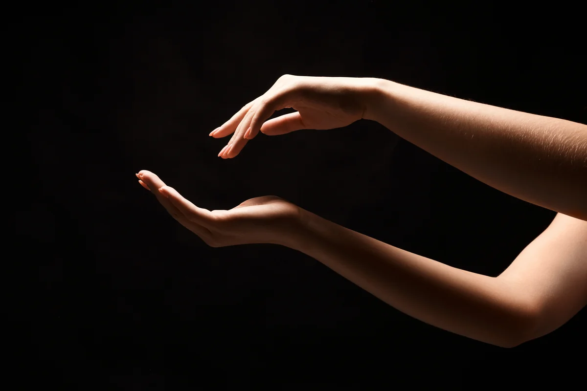 Mains féminines aux gestes gracieux éclairées sur un fond noir