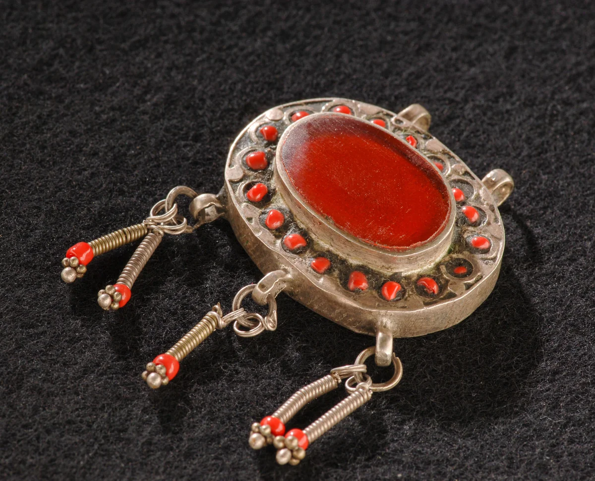 Pendentif ancien en argent serti d'une pierre rouge, sur fond noir